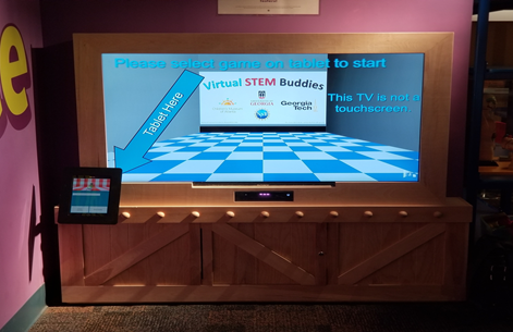 Virtual STEM Buddy Kiosk Large screen television with a tablet displaying a game.
